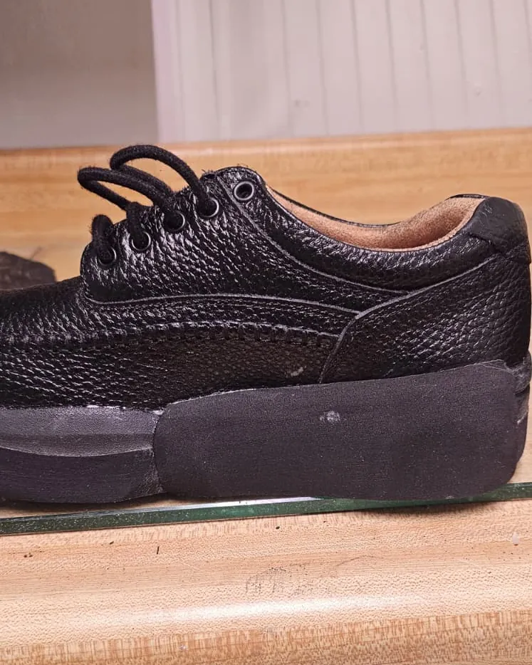 Black leather shoe with a lateral flare on the outer heel